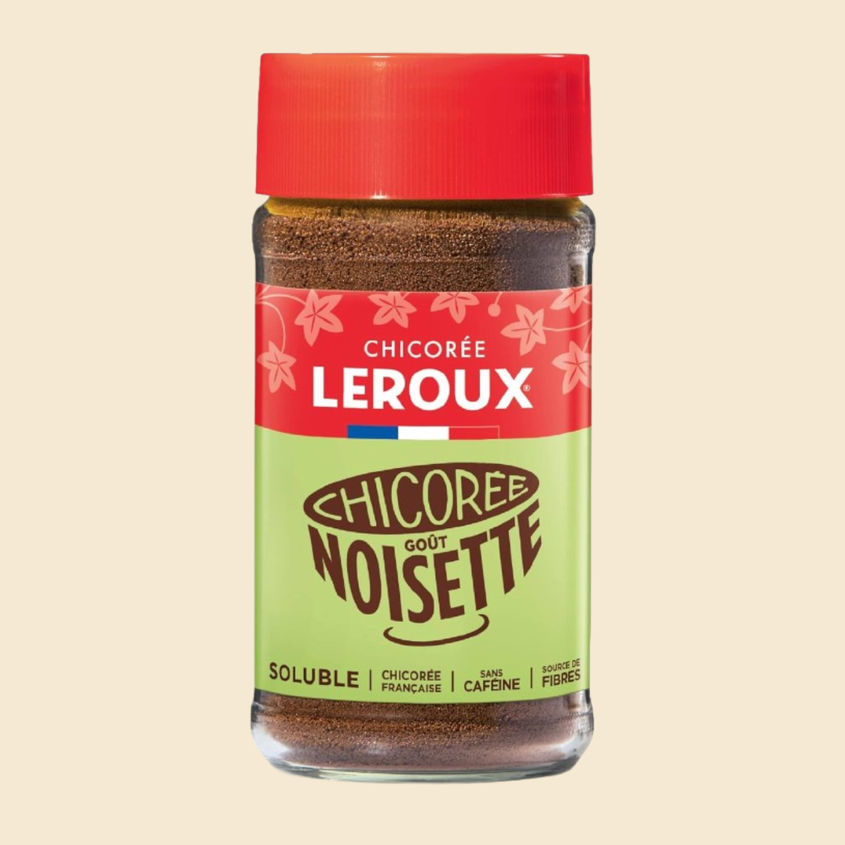 Bocal en verre de chicorée soluble goût noisette, marqué « Chicorée Leroux ». Couvercle rouge et étiquette rouge et verte avec texte blanc ; granulés bruns visibles à l’intérieur. Présence du drapeau français et mentions « sans caféine » et « source de fibres ».