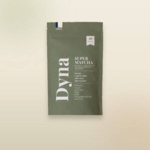 Sachet vert mat de Super Matcha Dyna présenté sur un fond beige clair. L’emballage indique 30 portions et met en avant une alternative au café à base de matcha, champignons et plantes adaptogènes. Les bénéfices affichés incluent énergie, concentration, anti-stress et antioxydant, avec des ingrédients comme le matcha bio, le guarana, le Lion’s Mane, le chaga, le reishi, l’ashwagandha KSM-66® et le lait de coco.