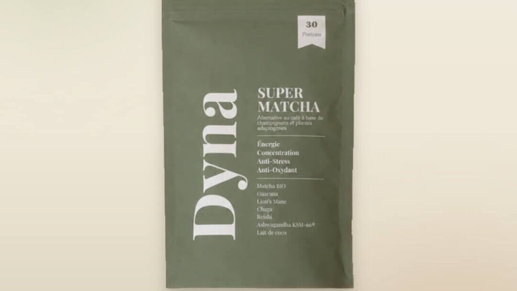 Sachet vert mat de Super Matcha Dyna présenté sur un fond beige clair. L’emballage indique 30 portions et met en avant une alternative au café à base de matcha, champignons et plantes adaptogènes. Les bénéfices affichés incluent énergie, concentration, anti-stress et antioxydant, avec des ingrédients comme le matcha bio, le guarana, le Lion’s Mane, le chaga, le reishi, l’ashwagandha KSM-66® et le lait de coco.